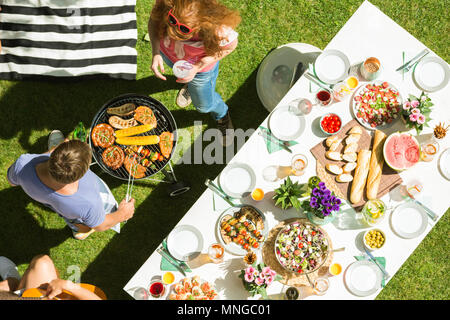 Man and woman grilling food for party garden, top view Stock Photo