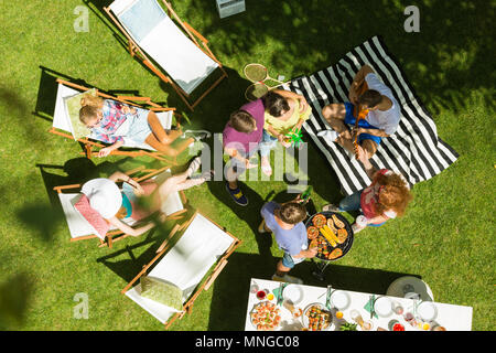 Friends relaxing in garden and grilling food, bird view Stock Photo
