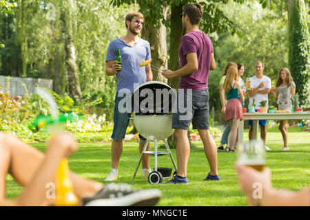 Two men standing beside barbecue grill in garden Stock Photo