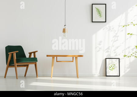 White home interior with green armchair, table, lamp, leaf posters Stock Photo