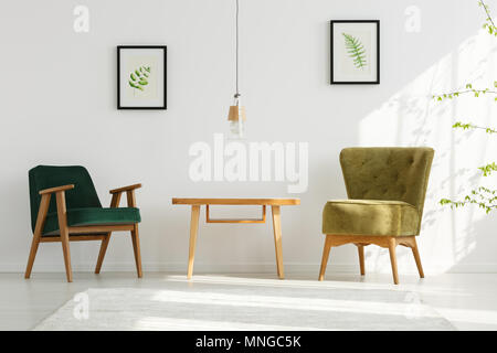 White apartment with green armchairs, table, lamp, leaf posters Stock Photo