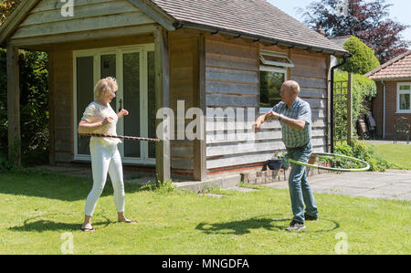 Man and woman using hula hoops for fitness and exercise in a garden setting. 2018.