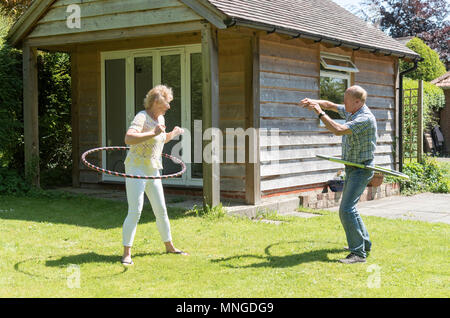 Man and woman using hula hoops for fitness and exercise in a garden setting. 2018. Stock Photo