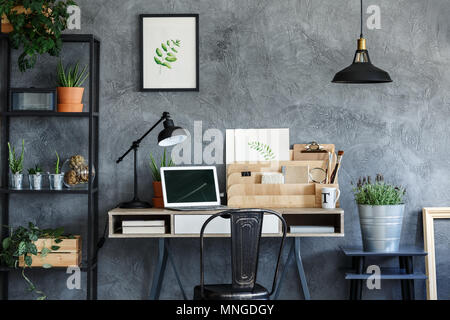 Vintage workshop with laptop, lamp, rack, botanical posters and plants Stock Photo