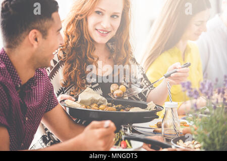 Red haired woman shares meal with her friend during meeting in restaurant Stock Photo