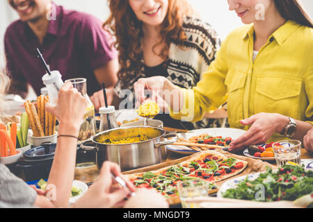 Woman in yellow shirt eats millet groats during lunch with friends in restaurant Stock Photo
