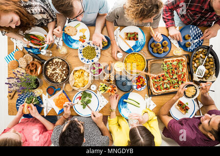 Man in violet shirt eats organic hummus during meeting with vegan friends Stock Photo