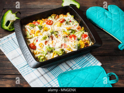 Baked pasta with broccoli and cheesy tomato sauce on wood background. Stock Photo