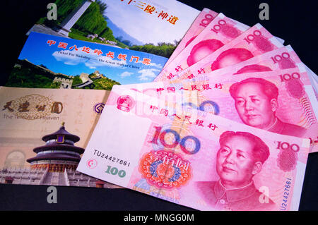 A display of Chinese 100 Yuan bank notes featuring the image of Mao Zedong with tickets for the Temple of Heaven, Great Wall & Ming Tombs in Beijing.. Stock Photo