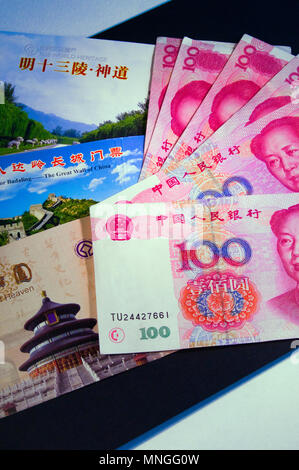 A display of Chinese 100 Yuan bank notes featuring the image of Mao Zedong with tickets for the Temple of Heaven, Great Wall & Ming Tombs in Beijing.. Stock Photo