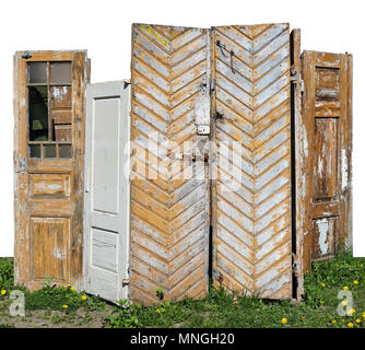 Rotten aged  wooden yellow and white doors are installed on a spring grassy glade with dandelions. Isolated on white with patch outdoor concept Stock Photo