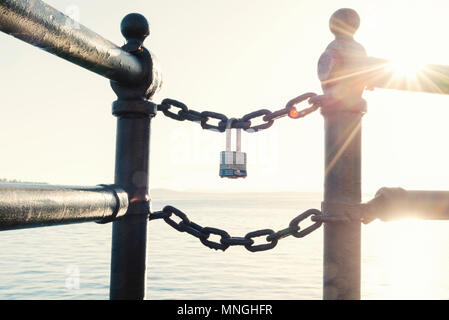 Steel lock locked to a chain with sunburst flare Stock Photo