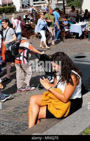 Copenhagen, Denmark - August 24, 2017: People outdoors walking in Nyhavn with a dark haired woman sitting in the foreground. Stock Photo