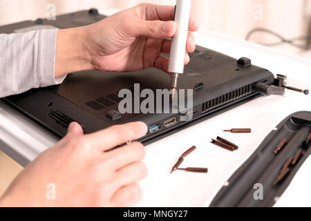 a women is repair laptop using screw driver, repair and maintenance Stock Photo