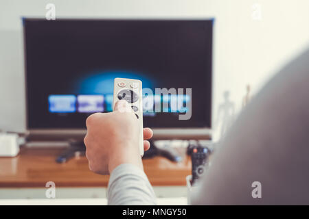 a women hand hold the remote control of the TV box in the living room Stock Photo