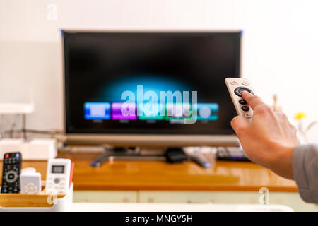 a women hand hold the remote control of the TV box in the living room, the black screen TV Stock Photo
