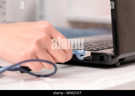 women hand is plugging in the lan cable to laptop port Stock Photo