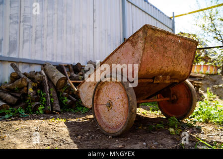 Obsolete wheelbarrow covered in rust kept in the garden Stock Photo