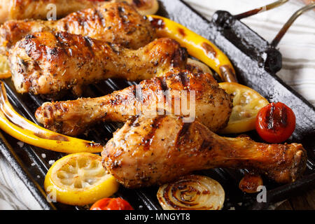 Freshly cooked grilled chicken drumstick legs with vegetables in a grill pan close-up on a table. horizontal Stock Photo