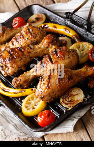 Fried chicken drumstick with vegetables in a grill pan close-up on a table. vertical Stock Photo