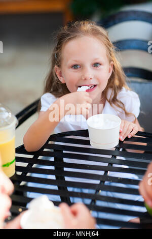 Little girl eating ice cream at outdoor cafe