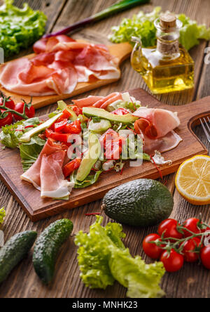 Salad with smoked ham and vegetables on wooden cutting board Stock Photo