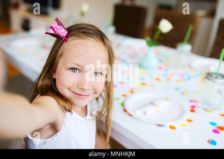 Adorable little girl with princess crown at kids birthday party making selfie Stock Photo