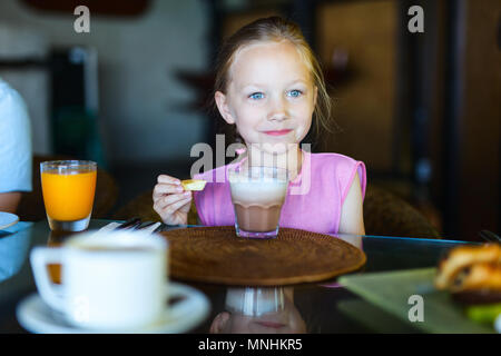 Adorable little girl in restaurant drinking hot chocolate Stock Photo