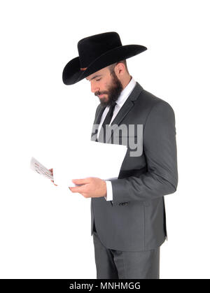A business man standing in profile in a gray suit and cowboy hat reading his papers, isolated for white background Stock Photo
