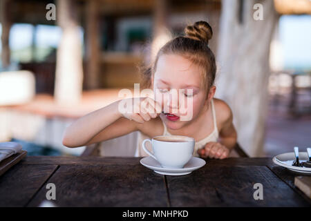 Adorable little girl in restaurant drinking hot chocolate Stock Photo