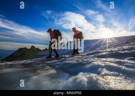 Two climbers descending glacier on slopes of Mount Shuksan at sunset, Washington State, USA Stock Photo
