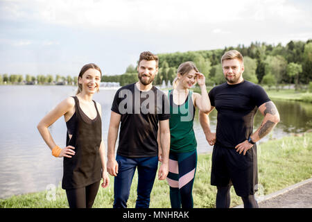 Portrait of a sports team standing together in the park near the lake Stock Photo