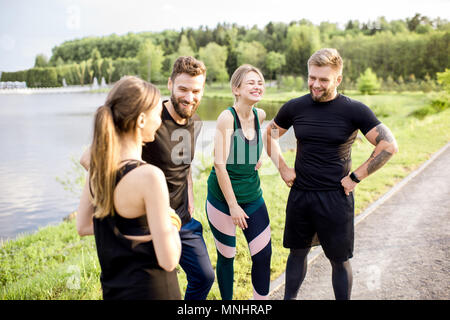 Sports team having fun standing together after the training outdors in the park near the lake Stock Photo