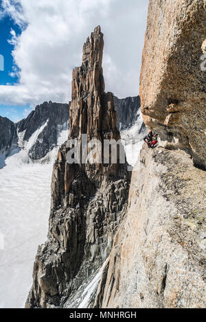 Climber crouching while ascending Grand Capucin pinnacle in Alps, Haute-Savoie, France Stock Photo