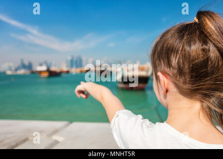 Back view of little girl enjoying panoramic view of Doha Qatar waterfront on sunny day Stock Photo
