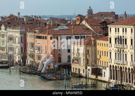 Venice, Italy - March 20, 2018: Giant hands rise from the water of Grand Canal to support the building in Venice. This powerful report on climate chan Stock Photo