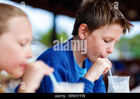 Kids brother and sister drinking milkshakes in outdoor cafe Stock Photo