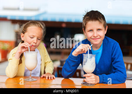 Kids brother and sister drinking milkshakes in outdoor cafe Stock Photo