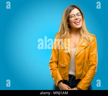 Beautiful young woman blinking eyes with happy gesture, blue background Stock Photo