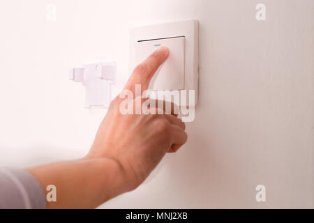 turning off/on the wall-mounted electric light switch. Stock Photo