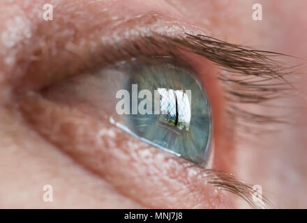 Closeup of man's eye looking out a window, with reflection in his eye.. Trapped. Looking out. Staying home. COVID19 lockdown, Coronavirus. Stock Photo