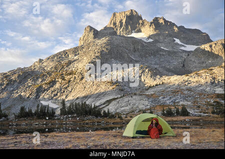 Backpacker In Her Sleeping Bag On Cold Morning At Camp Near