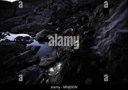 Backpackers with headlamps while passing waterfall at night near Mt Ritter on trek of Sierra High Route in Minarets Wilderness, Inyo National Forest, California, USA Stock Photo