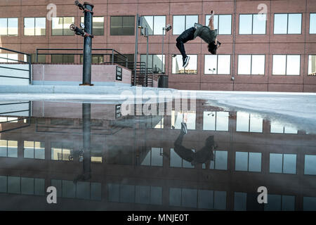 Park athlete in mid back flip in parking lot in downtown Denver, Colorado, USA Stock Photo