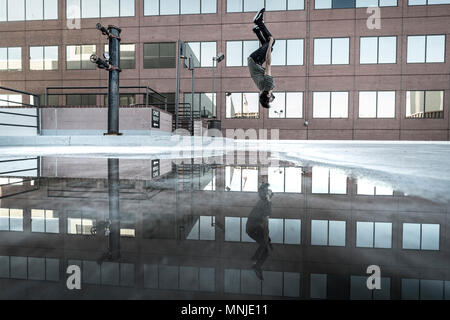 Park athlete in mid back flip in parking lot in downtown Denver, Colorado, USA Stock Photo