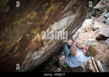 Young male rock climber preparing to climb boulder, Boulder, Colorado, USA Stock Photo