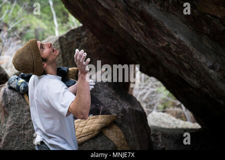 Side view of young male rock climber preparing to climb boulder, Boulder, Colorado, USA Stock Photo
