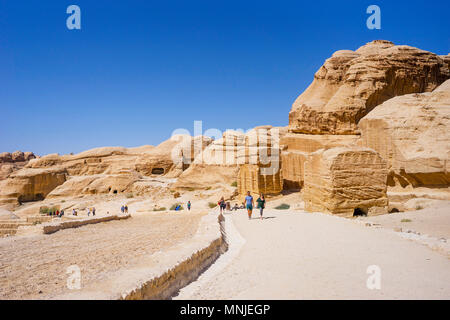 Tourists walking on footpath entering Petra from Visitors Center with tombs and temples carved in sandstone, Wadi Musa, Maan Governorate, Jordan Stock Photo