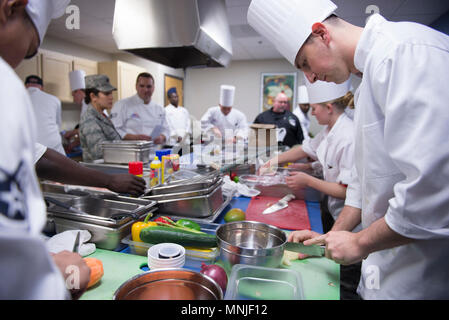 Chefs square off against each other by preparing meals in the Community Commons kitchen during the 2018 Grill Master competition at Luke Air Force Base, Ariz., Feb. 23, 2018. The Grill Master competition invited teams of two Airmen from units across the base to cook the best meal they could make out of fresh ingredients and a unique secret ingredient assigned to each team. Stock Photo