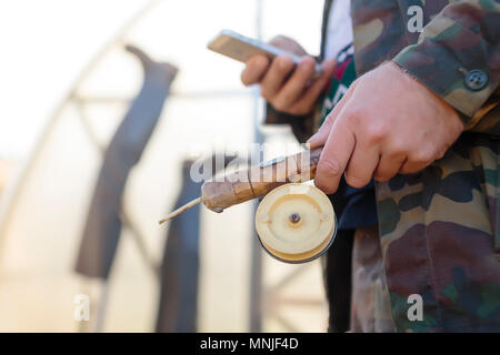 Side view of hands of man holding fishing rod and smartphone Stock Photo